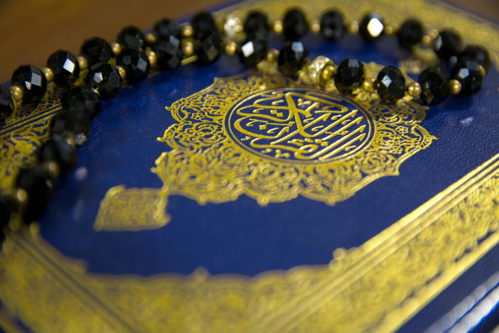 Close-up image of the Quran with black prayer beads on a blue cover, symbolizing Islamic faith.